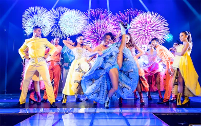 Dancers performing French Cancan at Paradis Latin in Cancun with fireworks in the background.