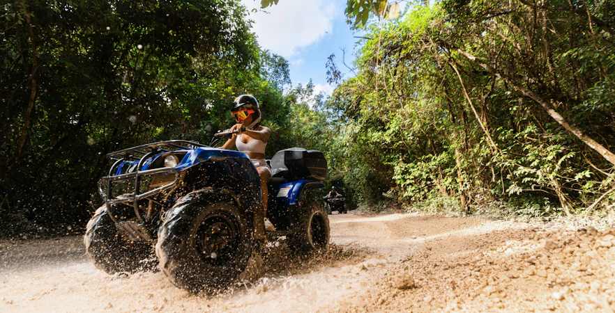 ATV rider navigating a muddy trail in Cancun's jungle adventure park.