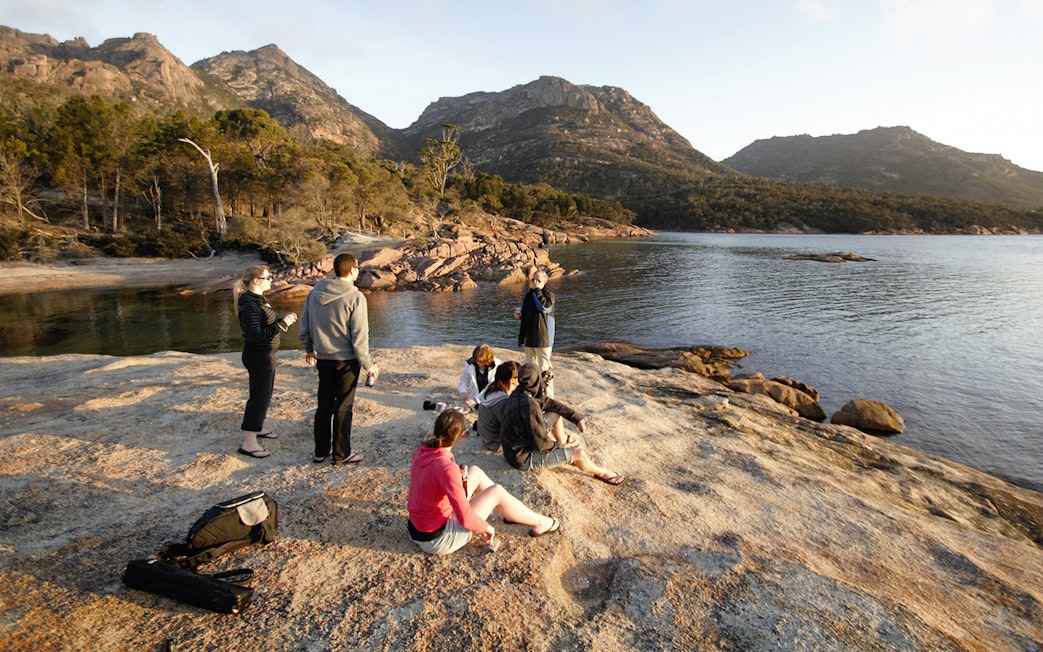Group enjoying the view at Wineglass Bay, Tasmania, with mountains in the background.