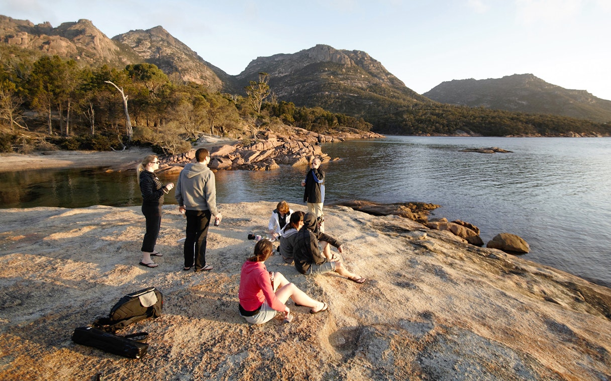 Group enjoying the view at Wineglass Bay, Tasmania, with mountains in the background.