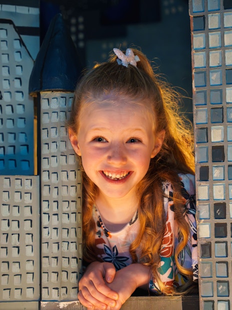 Child smiling between wax museum exhibits at the National Wax Museum.