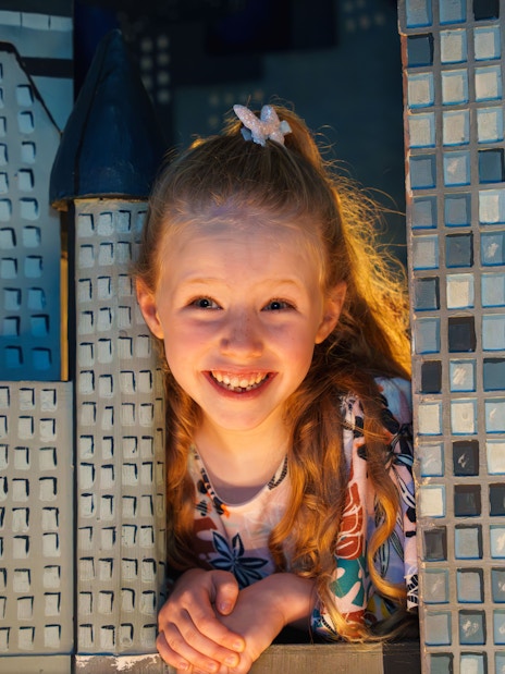 Child smiling between wax museum exhibits at the National Wax Museum.