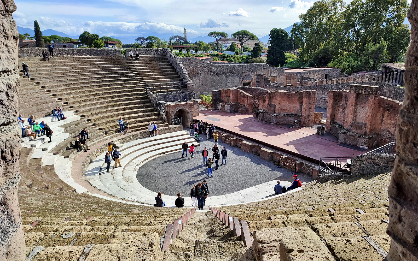 Ancient amphitheater in Pompeii with tourists exploring the site.