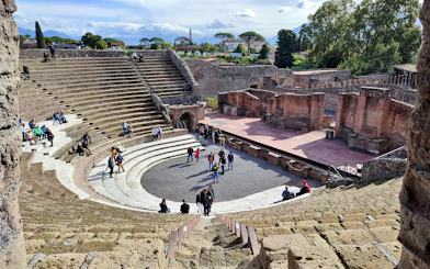 Ancient amphitheater in Pompeii with tourists exploring the site.