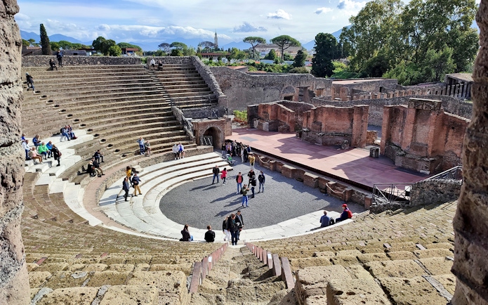 Ancient amphitheater in Pompeii with tourists exploring the site.