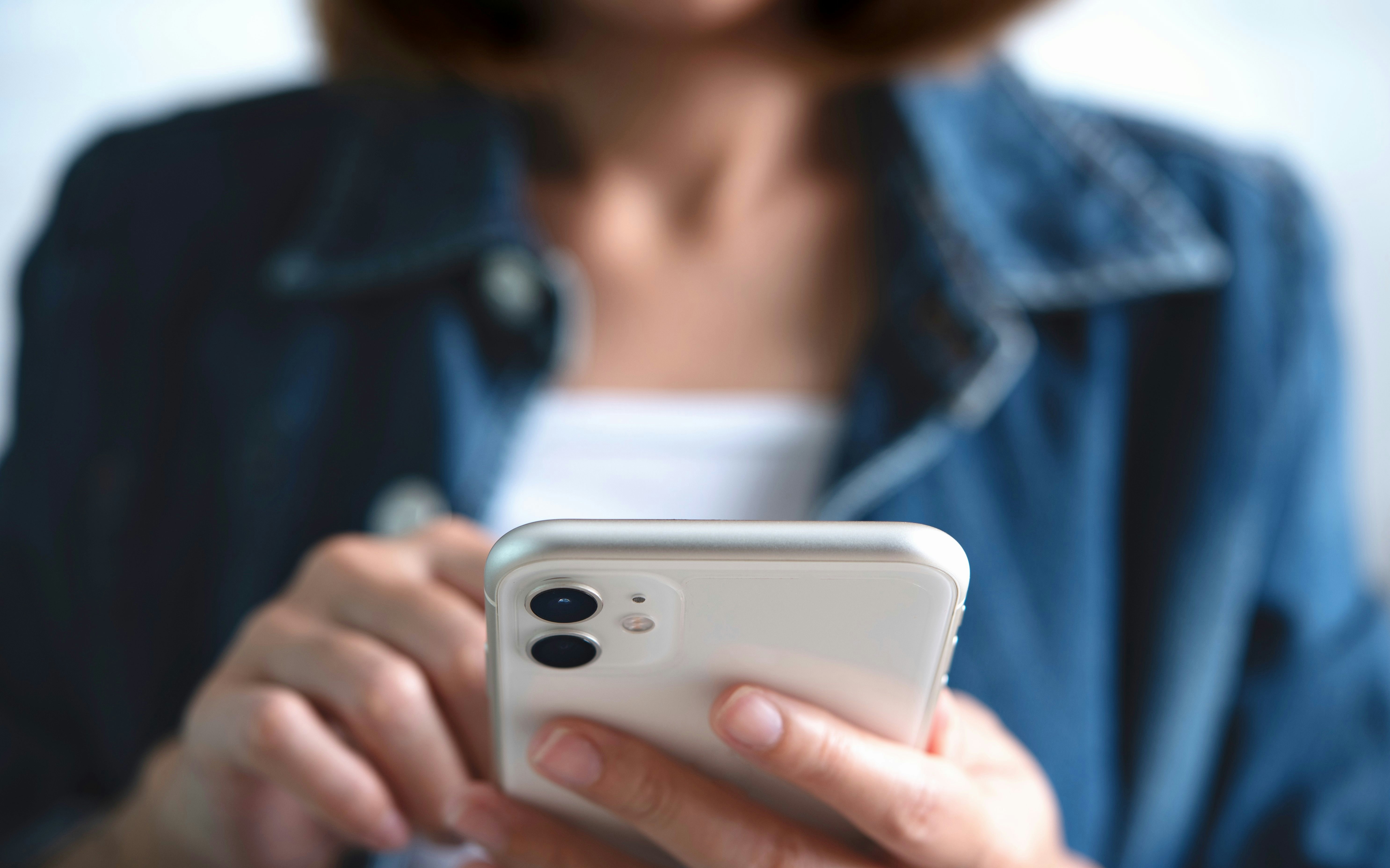 Young woman using smartphone, close-up of hands.