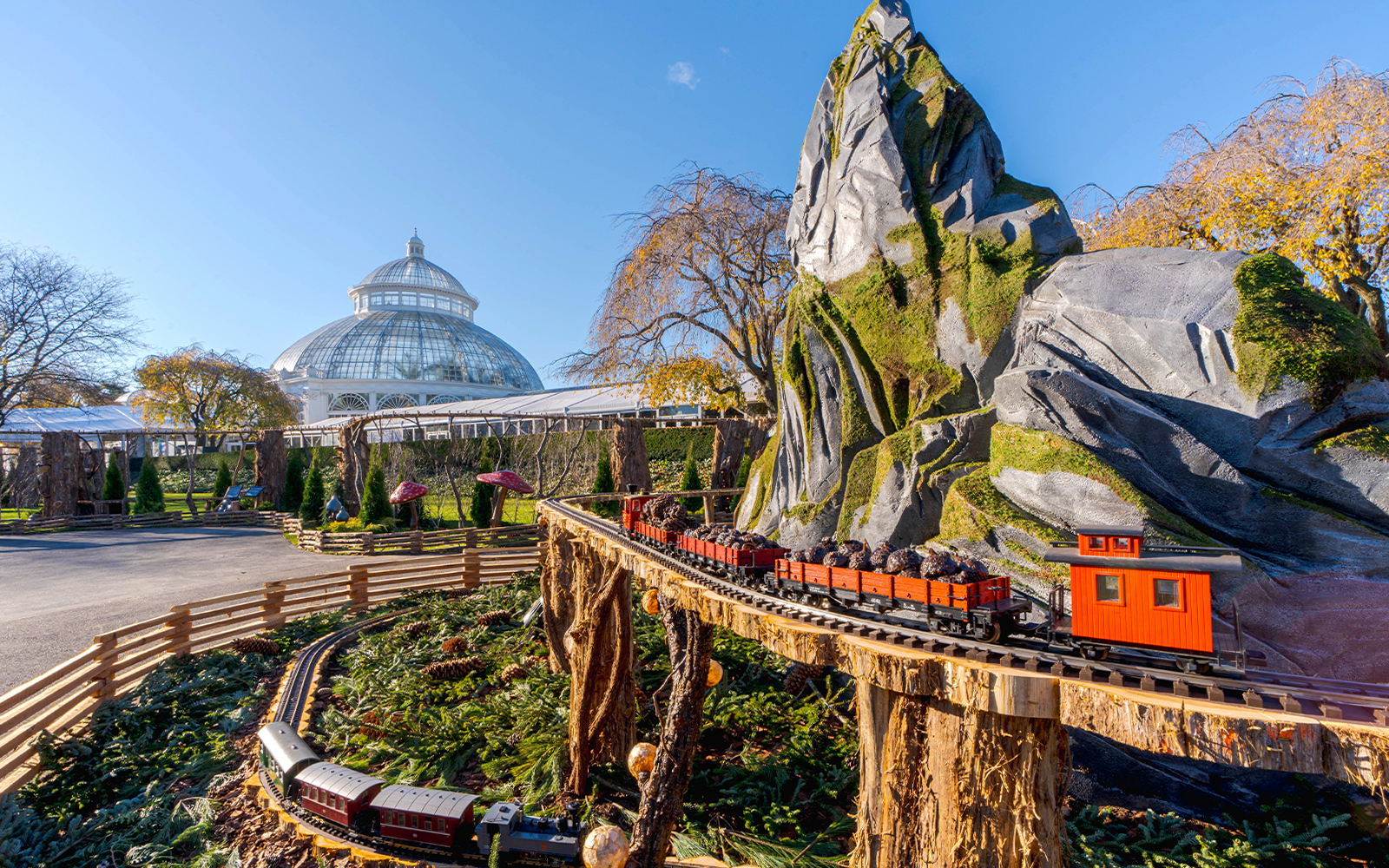 Holiday Train Show model train at New York Botanical Gardens with conservatory in background.