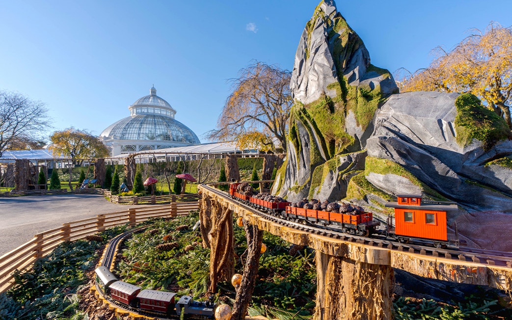 Holiday Train Show model train at New York Botanical Gardens with conservatory in background.