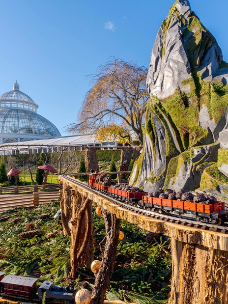 Holiday Train Show model train at New York Botanical Gardens with conservatory in background.