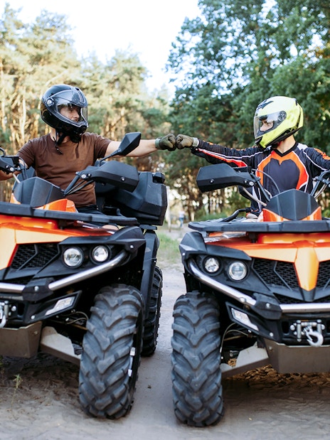 Two people on quad bikes in a forest near Zakopane, Poland, fist-bumping.