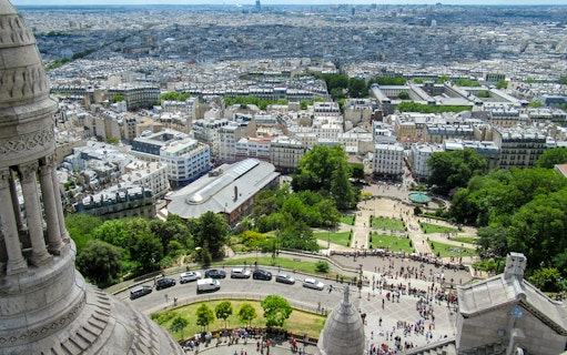 View of Paris from Montmartre Sacré-Cœur Cathedral, overlooking cityscape and gardens.