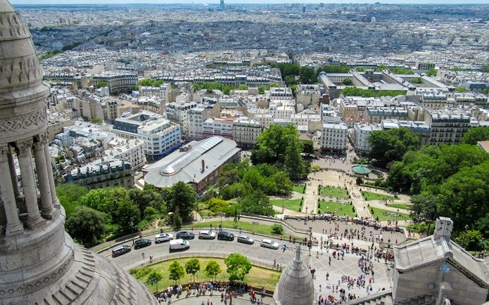 View of Paris from Montmartre Sacré-Cœur Cathedral, overlooking cityscape and gardens.