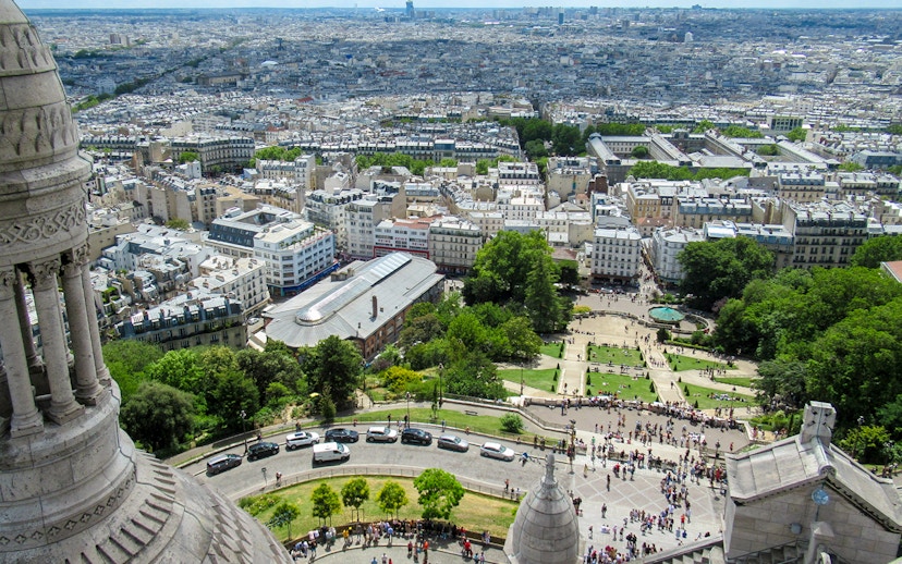 View of Paris from Montmartre Sacré-Cœur Cathedral, overlooking cityscape and gardens.