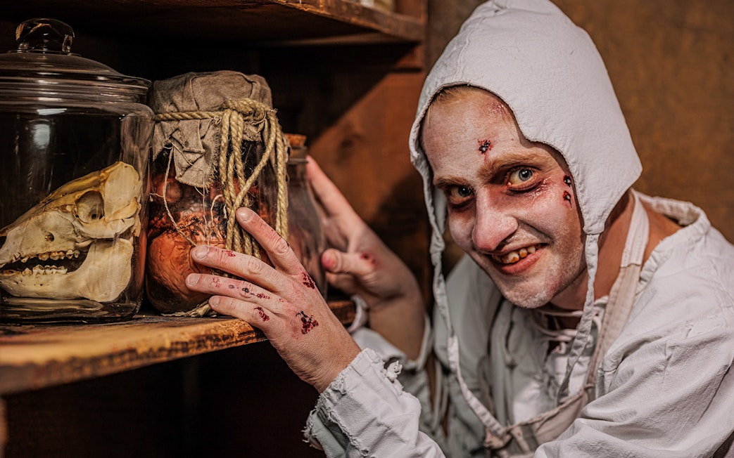 Plague doctor character with jars at Berlin Dungeon exhibit.