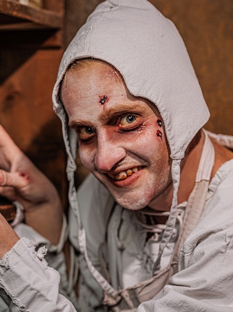 Plague doctor character with jars at Berlin Dungeon exhibit.