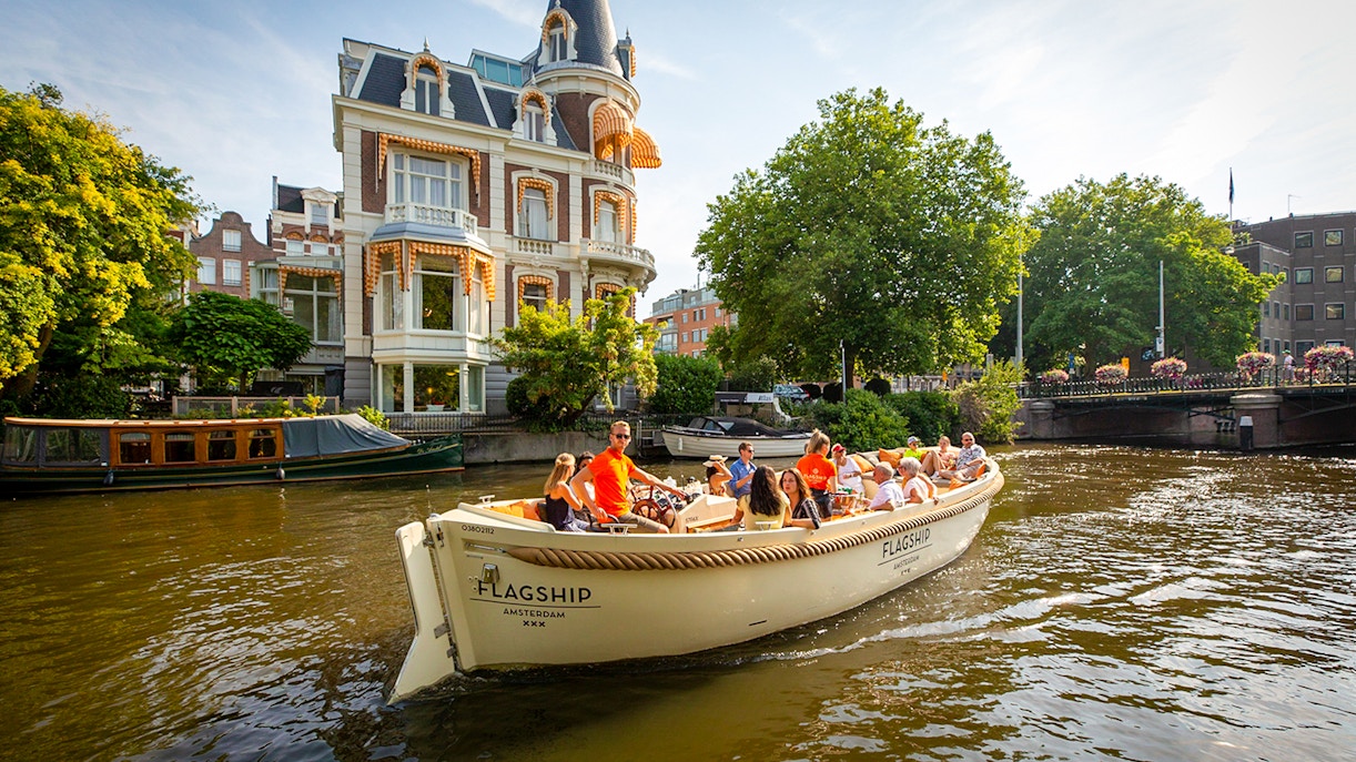 Luxury boat cruising Amsterdam canal near historic building.