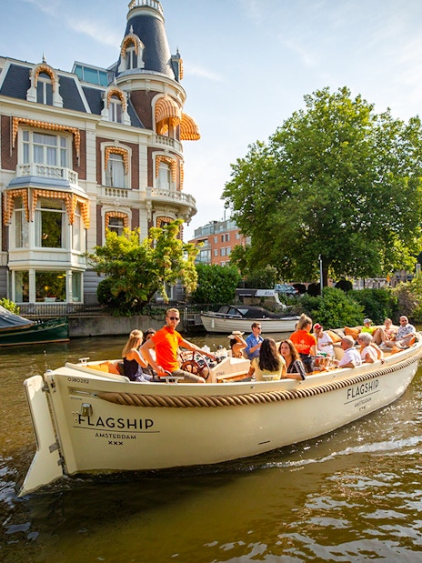 Luxury boat cruising Amsterdam canal near historic building.