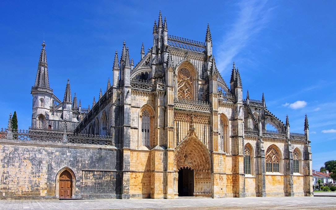 Batalha Monastery's intricate Gothic facade under a clear blue sky, Lisbon.