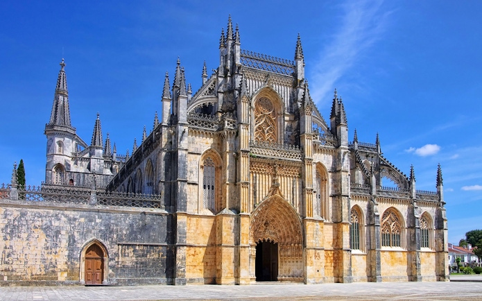 Batalha Monastery's intricate Gothic facade under a clear blue sky, Lisbon.