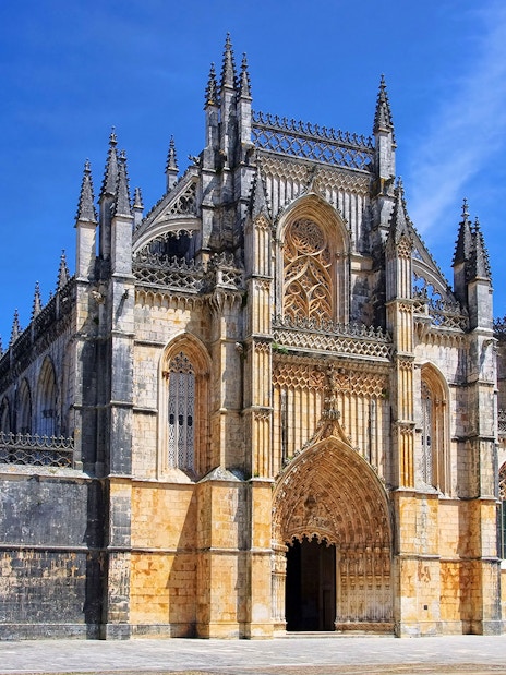 Batalha Monastery's intricate Gothic facade under a clear blue sky, Lisbon.