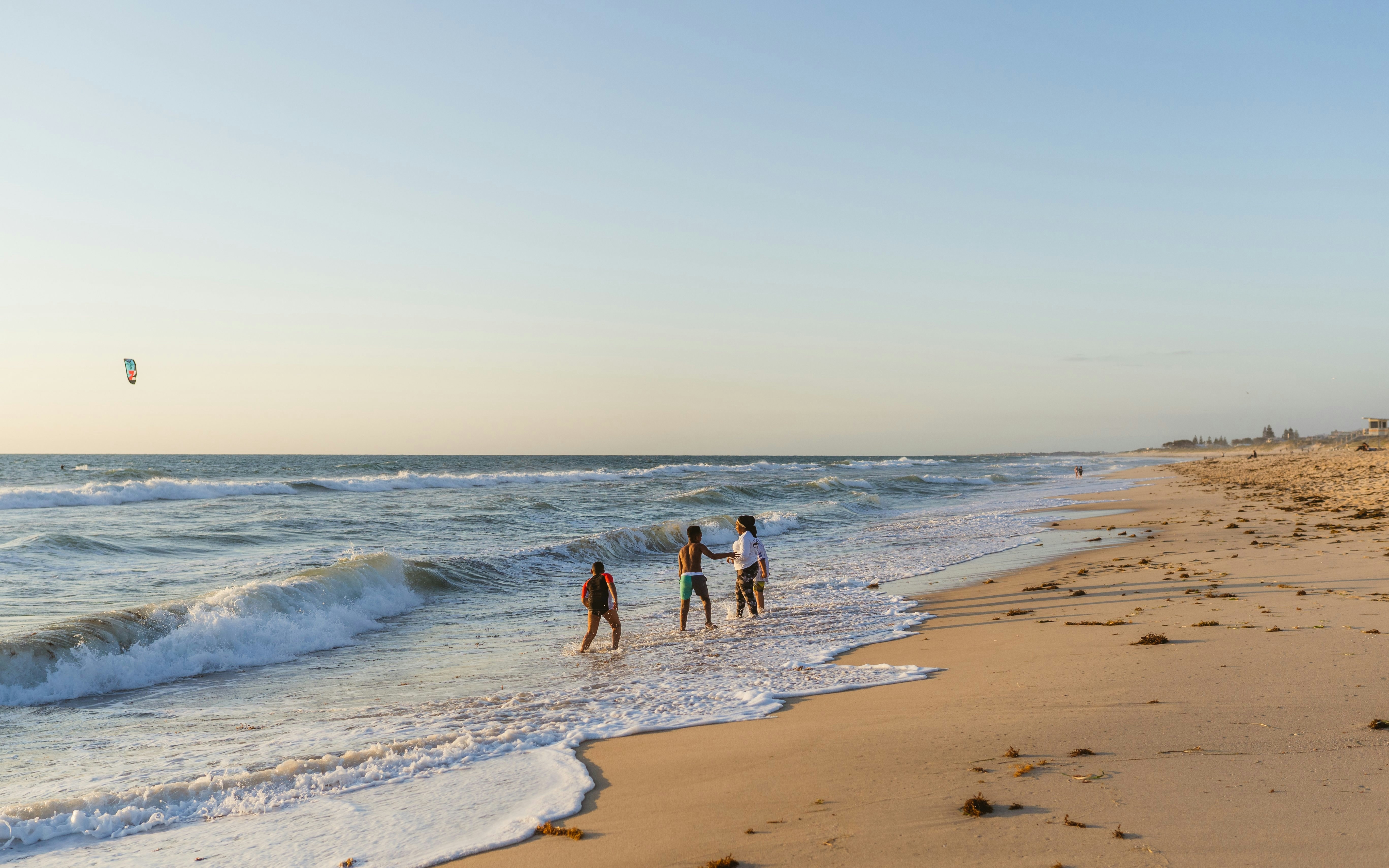 Children playing in shallow waves at sunset on Scarborough Beach, Perth.