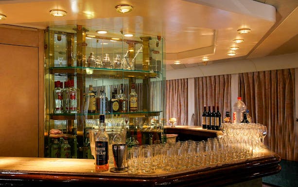 Bar area on The Cruise Club Tokyo night cruise with bottles and glasses displayed.