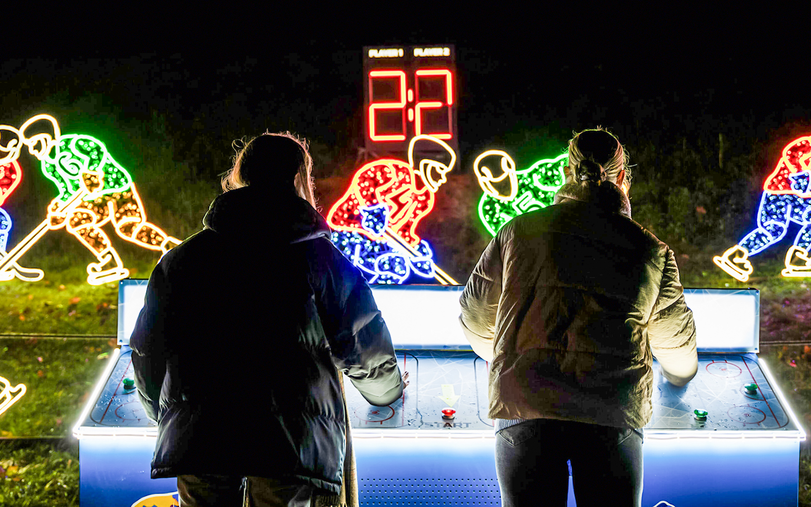 Visitors playing air hockey at Lumina Park Wonderworld with illuminated hockey player displays.