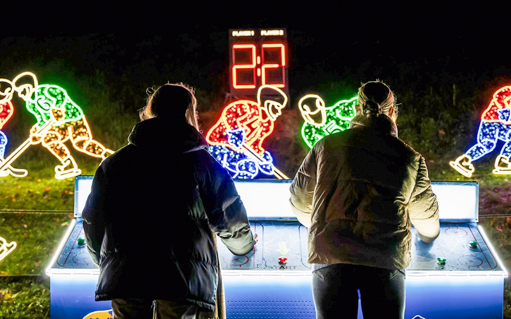 Visitors playing air hockey at Lumina Park Wonderworld with illuminated hockey player displays.