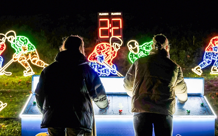 Visitors playing air hockey at Lumina Park Wonderworld with illuminated hockey player displays.