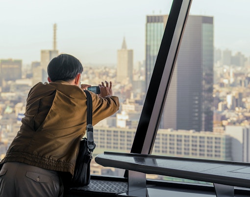 Tourist taking photo of city from the observation deck of Tokyo tower