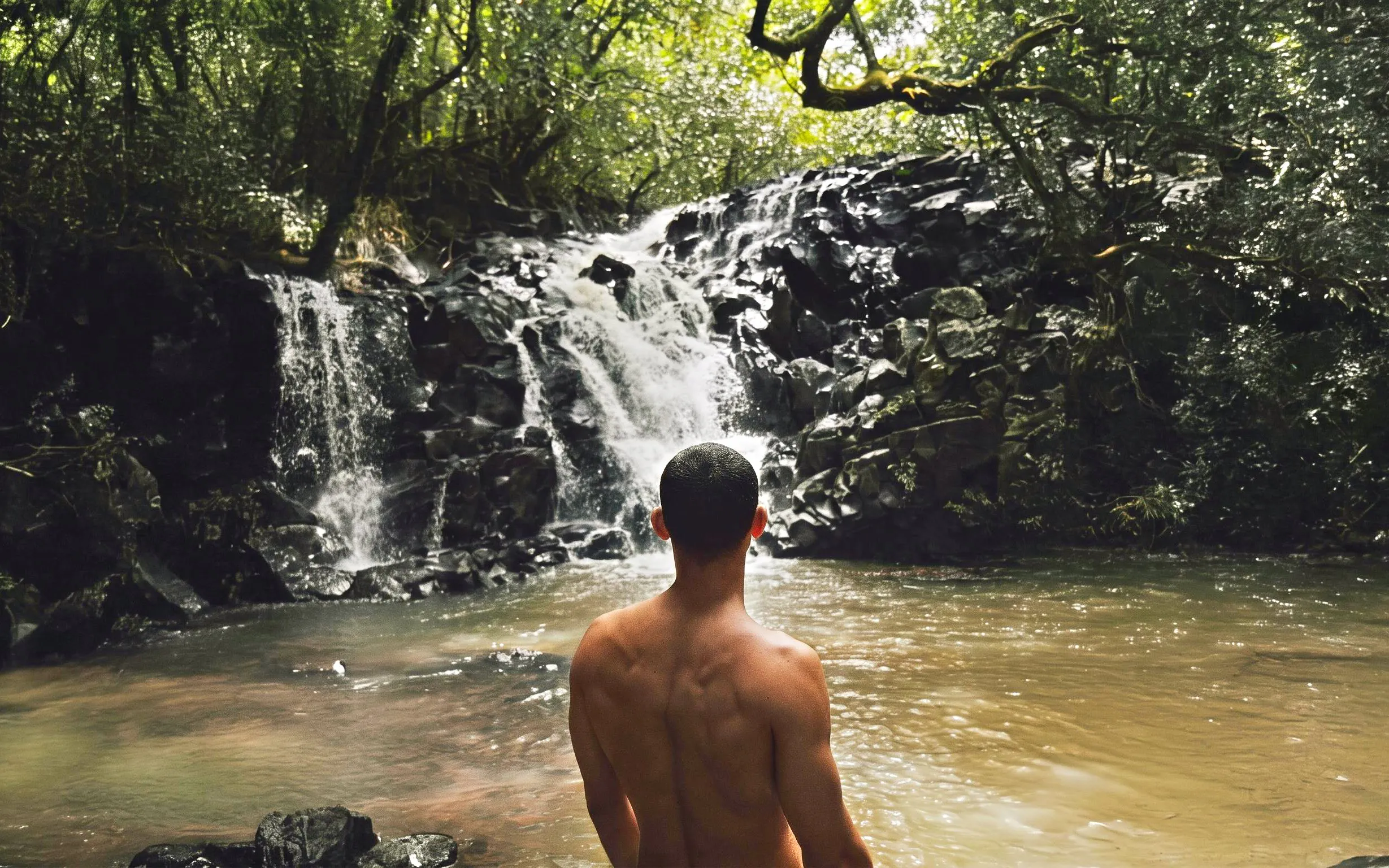 Person standing by a waterfall on the Bel Ombre walking trail.