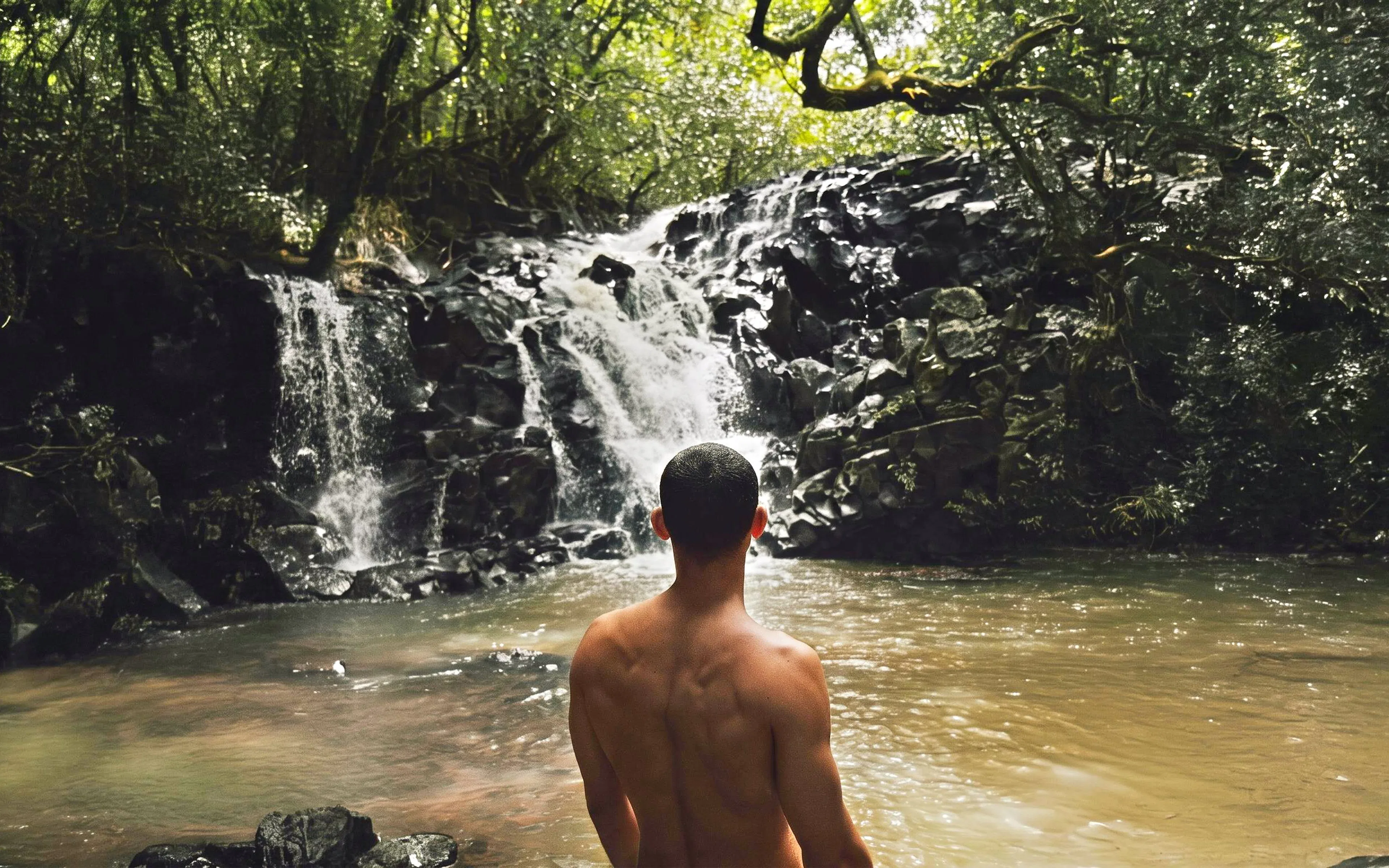 Person standing by a waterfall on the Bel Ombre walking trail.