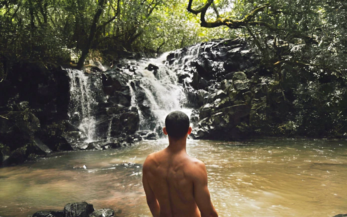 Person standing by a waterfall on the Bel Ombre walking trail.