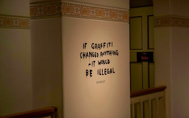 Banksy artwork with text "If graffiti changed anything it would be illegal" on a wall.