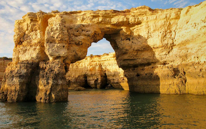 Rocky arch formation along Algarve coast during sunset on sailing tour from Vilamoura.