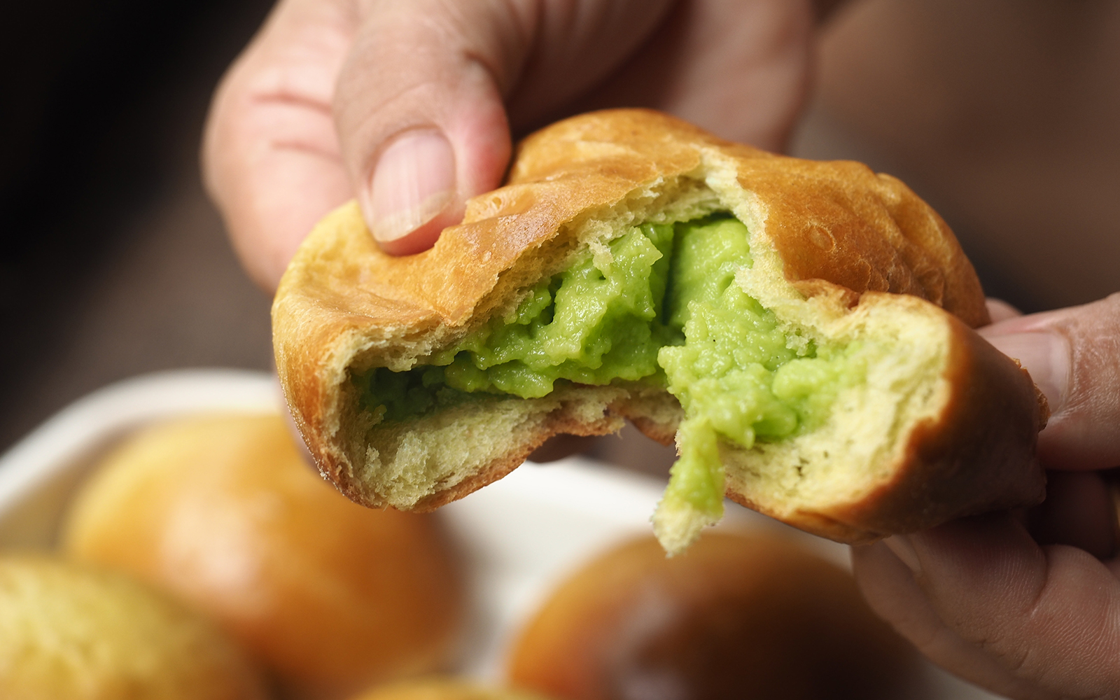 Hand pulling brioche bread bun with green pandan sangkhaya custard cream filling