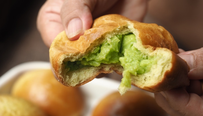 Hand pulling brioche bread bun with green pandan sangkhaya custard cream filling