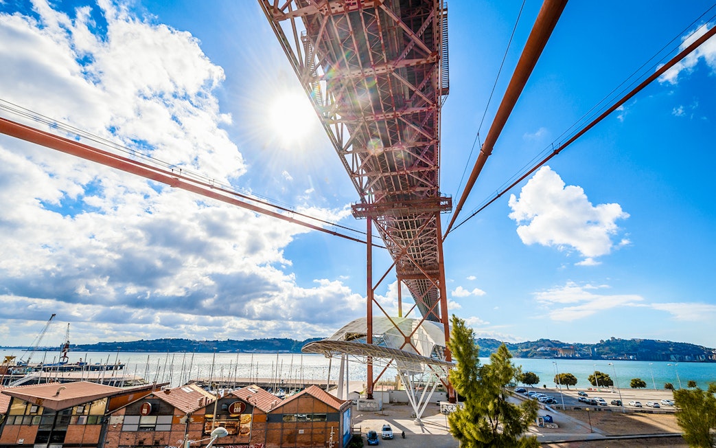 Underneath view of the Pilar 7 Bridge Experience in Lisbon, Portugal, with river and cityscape.