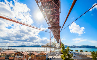 Underneath view of the Pilar 7 Bridge Experience in Lisbon, Portugal, with river and cityscape.