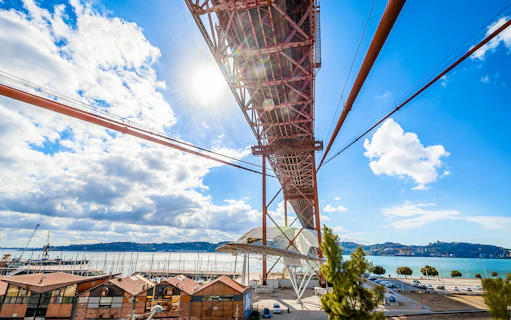 Underneath view of the Pilar 7 Bridge Experience in Lisbon, Portugal, with river and cityscape.