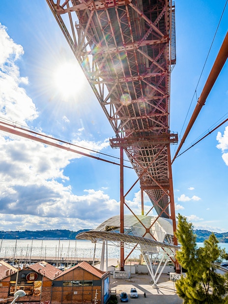 Underneath view of the Pilar 7 Bridge Experience in Lisbon, Portugal, with river and cityscape.
