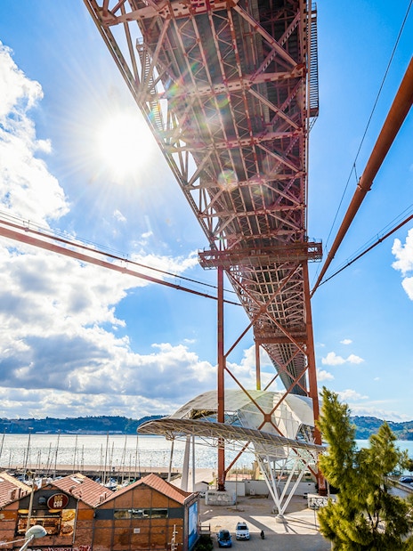 Underneath view of the Pilar 7 Bridge Experience in Lisbon, Portugal, with river and cityscape.