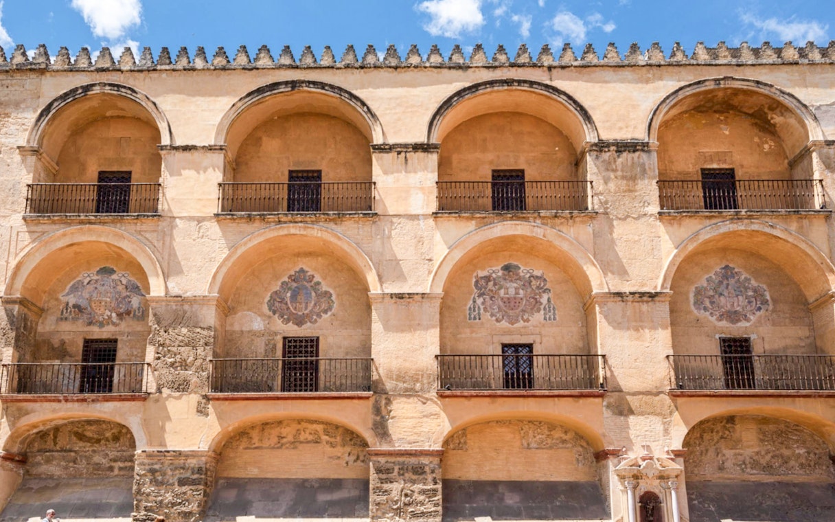 Exterior arches of Cordoba Mosque-Cathedral, Spain, with decorative emblems.