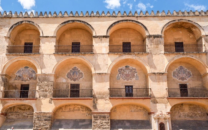 Exterior arches of Cordoba Mosque-Cathedral, Spain, with decorative emblems.
