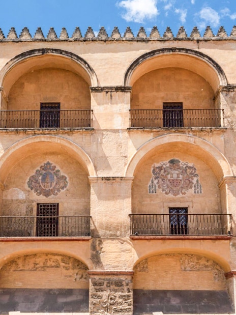 Exterior arches of Cordoba Mosque-Cathedral, Spain, with decorative emblems.