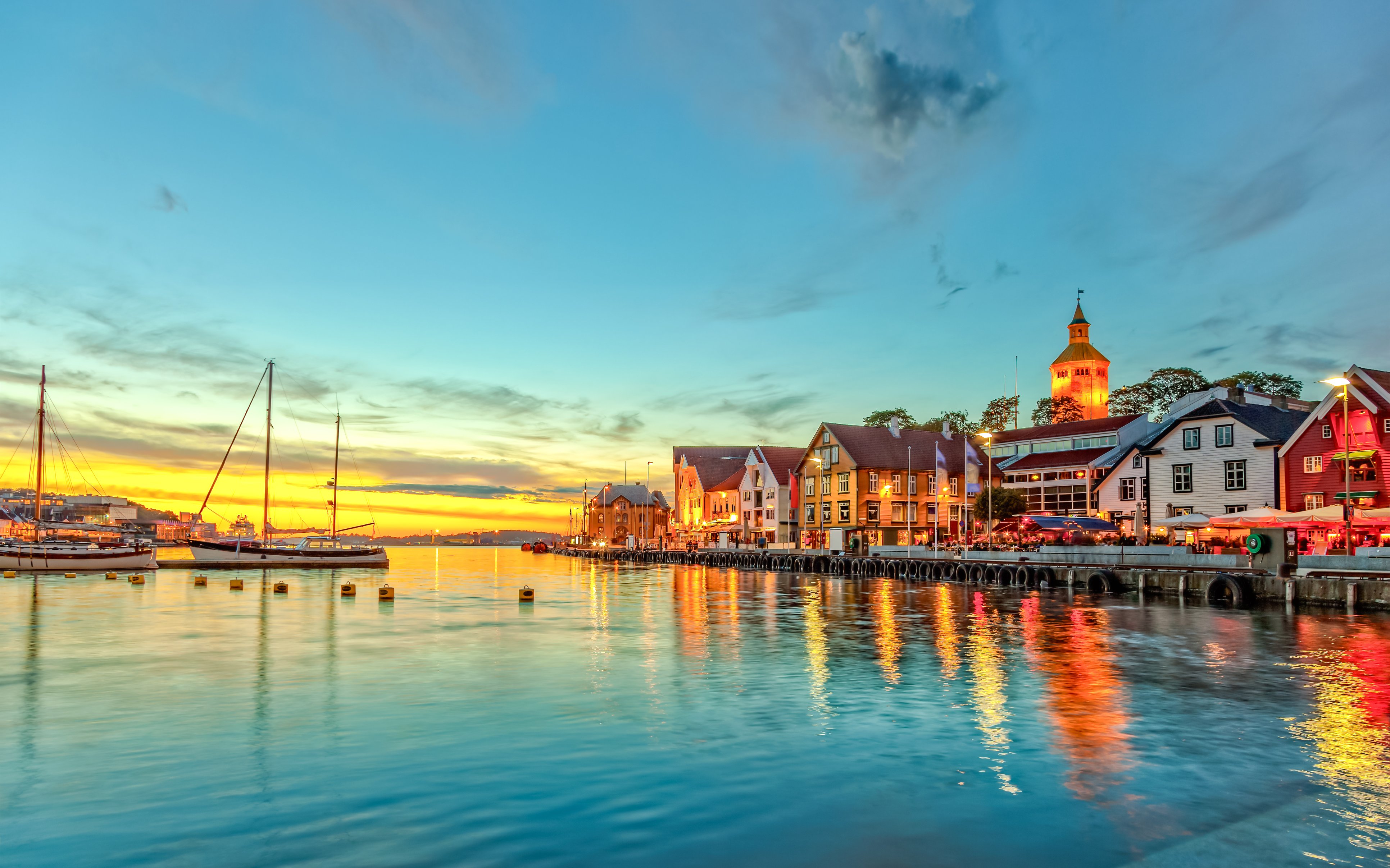 Stavanger harbor with boats and colorful buildings at sunset.
