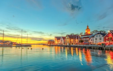 Stavanger harbor with boats and colorful buildings at sunset.