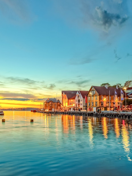 Stavanger harbor with boats and colorful buildings at sunset.