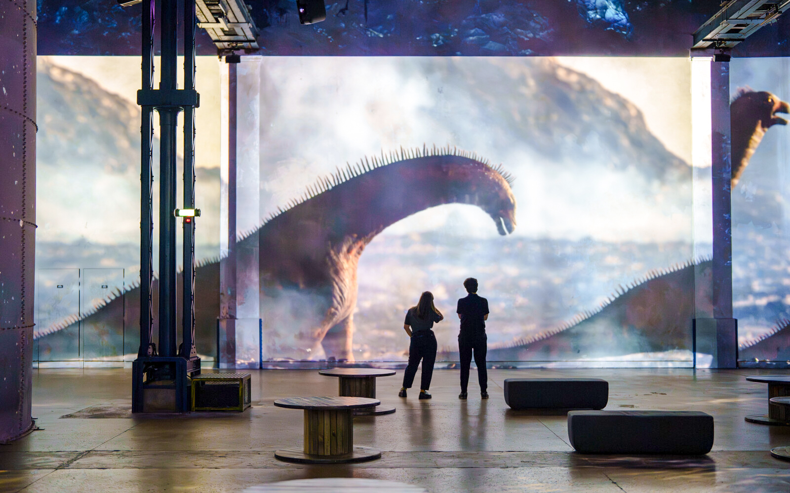 Visitors viewing dinosaur projection at Prehistoric Planet exhibition, Atelier des Lumières, Paris.
