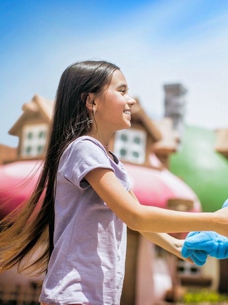 Child interacting with a blue character at a Dubai theme park.